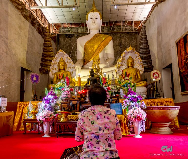 A woman is making a wish to the image of Lord Buddha