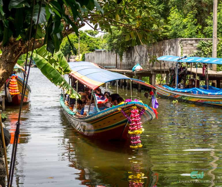 Tourists take a long-tail boat through a canal in Bangkok