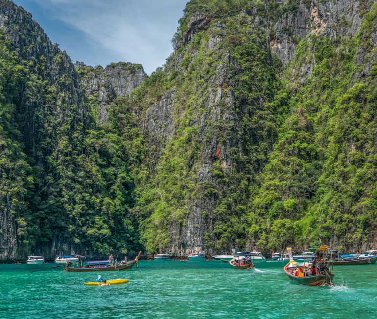 Small boats are heading to limestone canyon in an island in Krabi