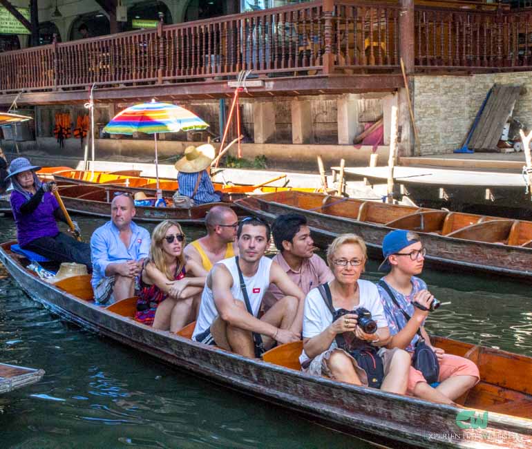 A local paddles her traditional boat taking tourists through the Damnoen Saduak floating market