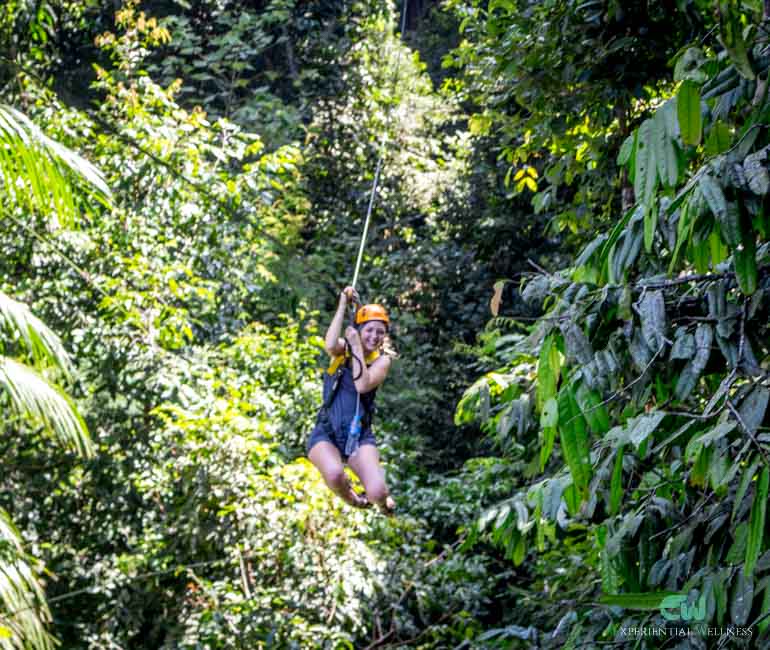 A tourist flies from trees to trees, enjoying her ziplining activity