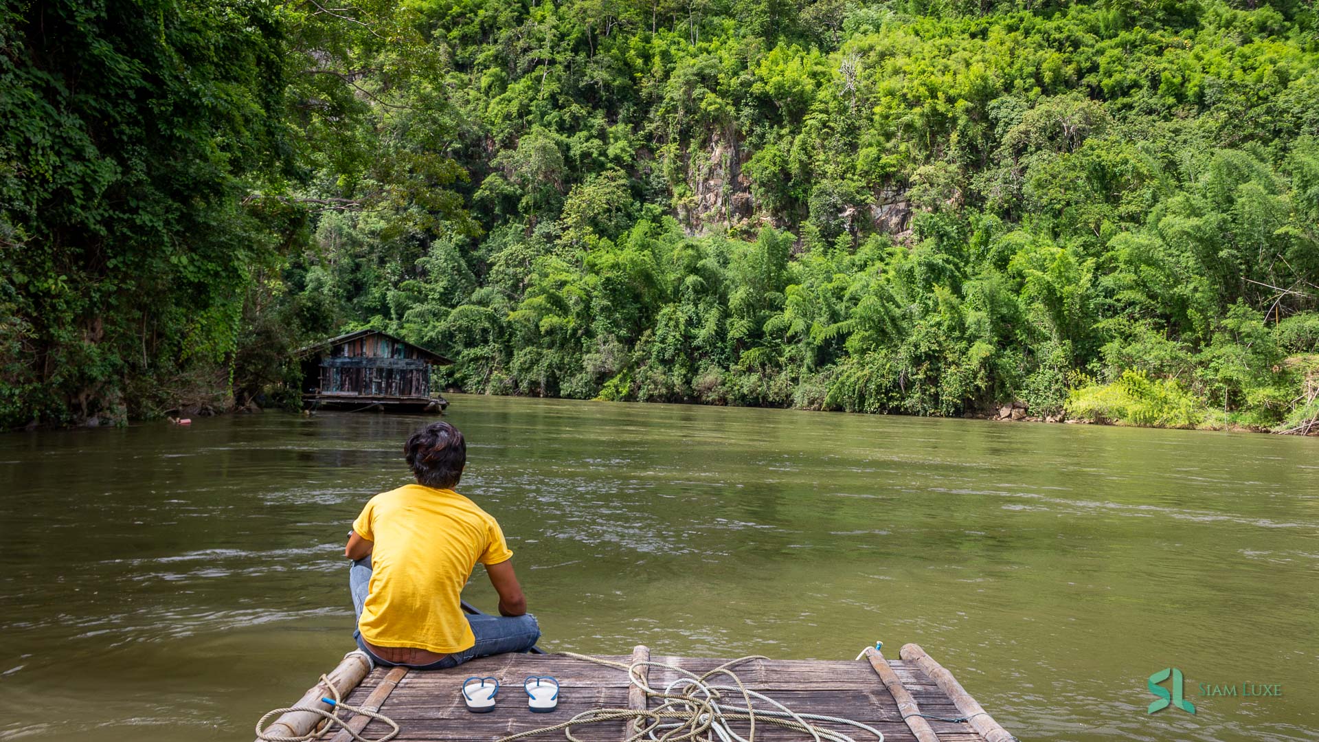 Our raftman is relaxing on his bamboo raft while the tourists are also chilling along the Khwae River