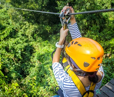 A girl enjoy her zipline activity through the jungle in Central Thailand